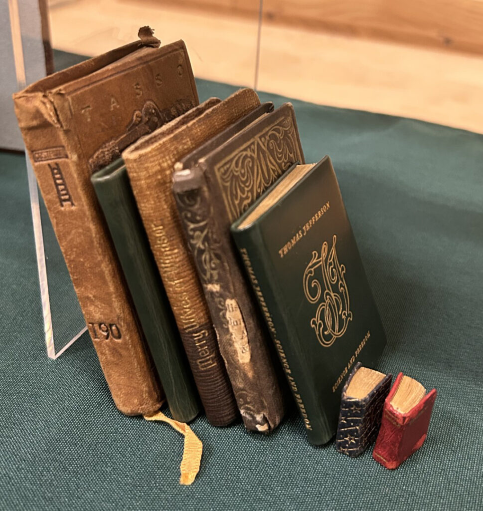miniature books measuring mere inches — shown next to standard sized texts for comparison