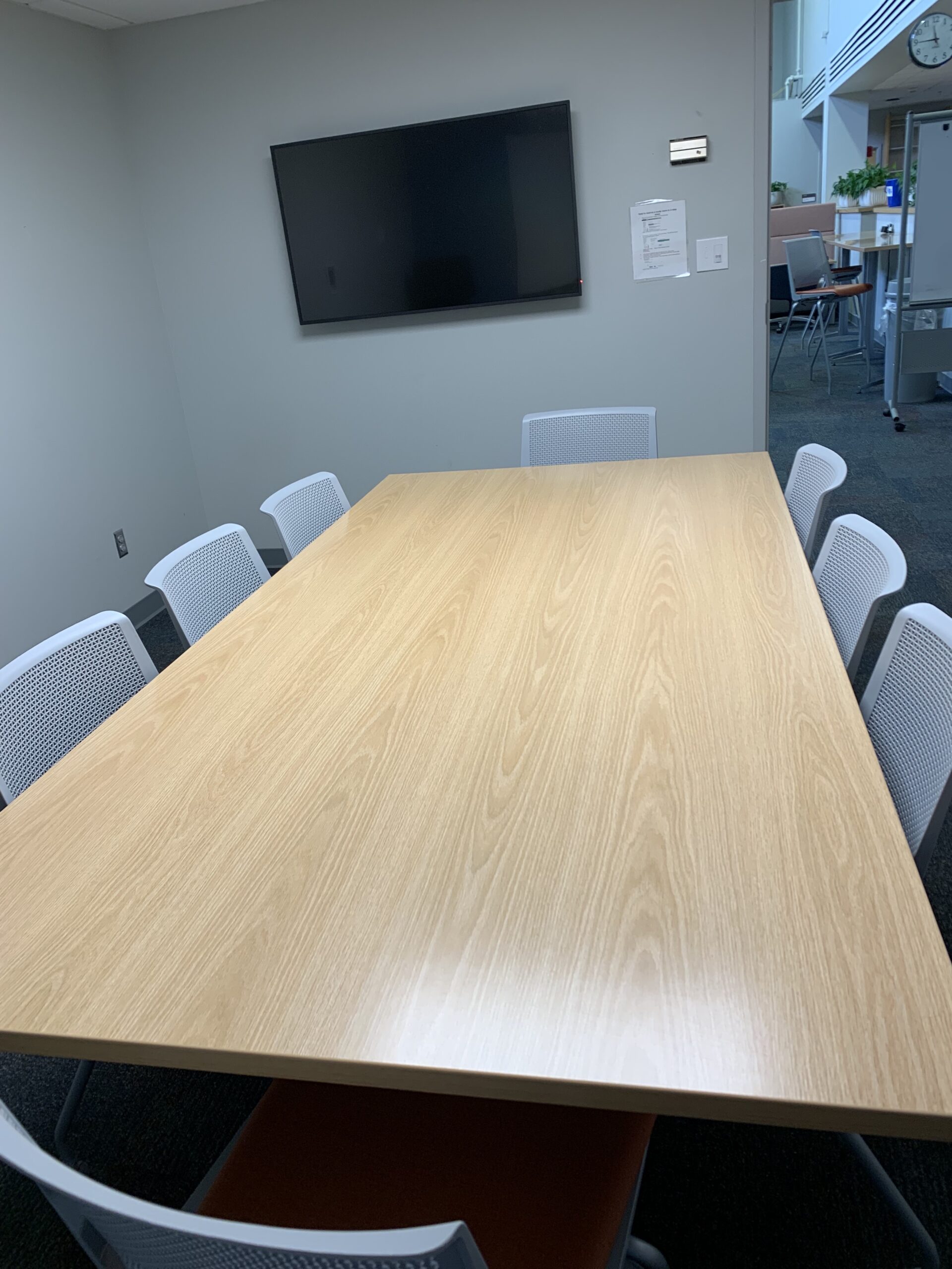 table with 8 chairs and an external display monitor mounted to the wall