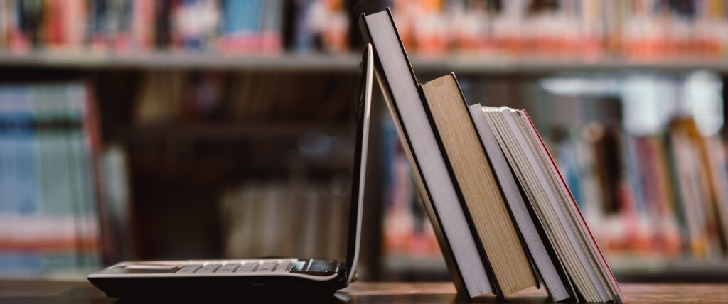 Laptop computer and book on the workplace in a library room